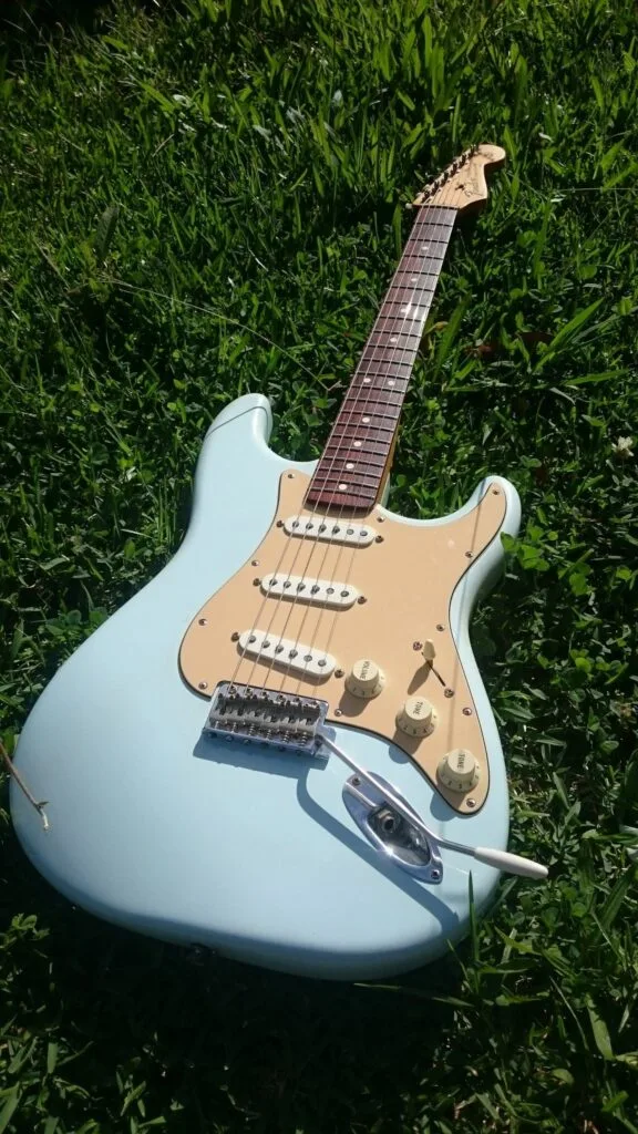 Sonic blue Fender Stratocaster electric guitar resting outside on green grass