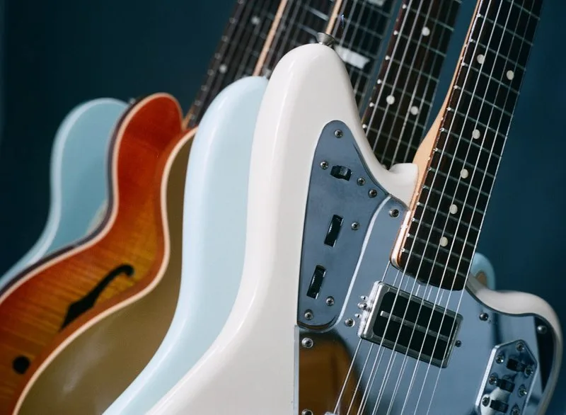 A row of various electric guitar bodies lined up on a rack for adult beginners choosing their first instrument