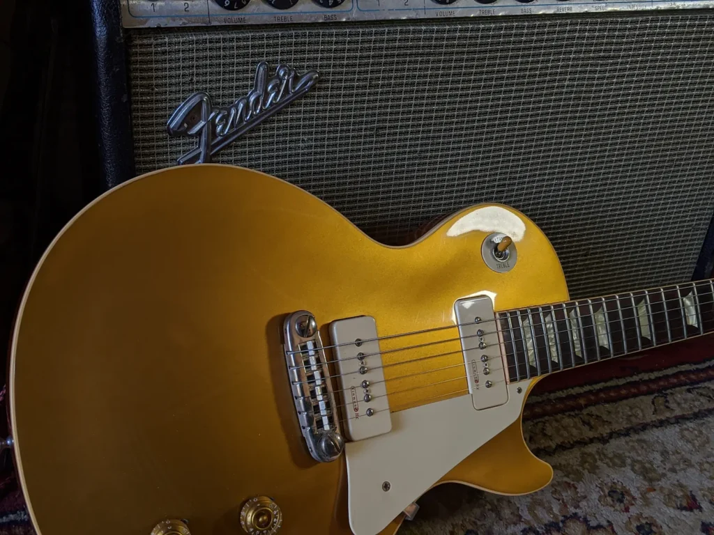 Gibson Les Paul Goldtop guitar leaning against a Fender Deluxe Reverb amplifier for guitar lessons