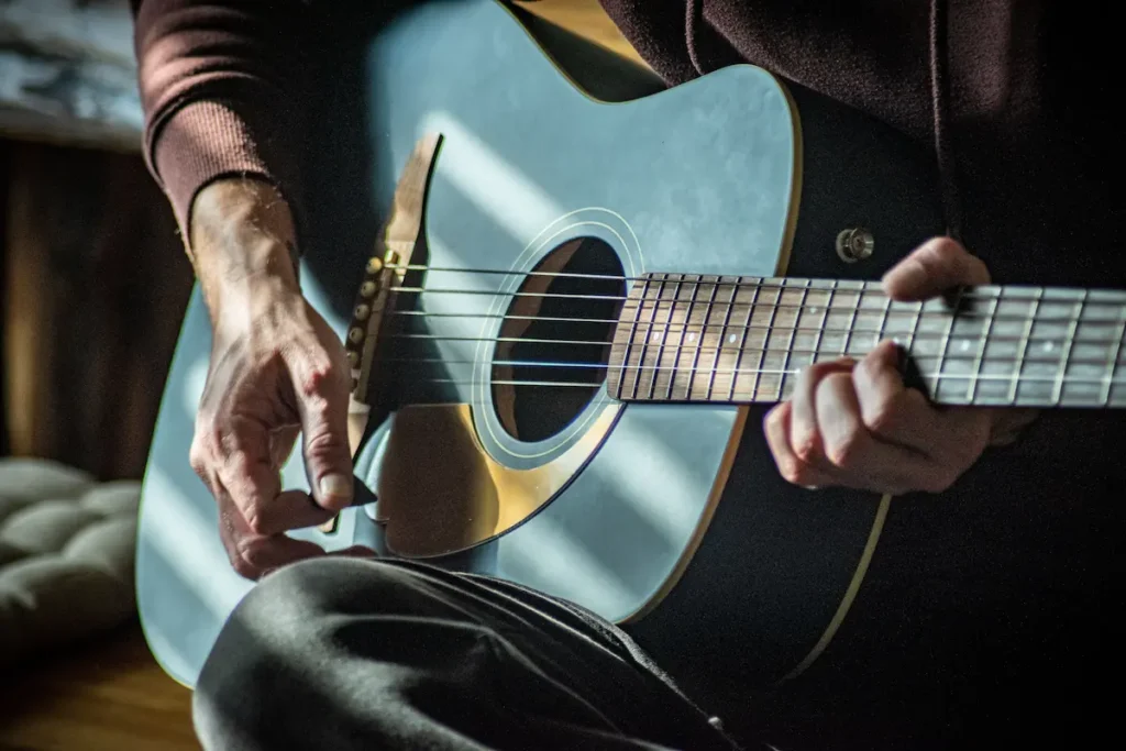 Close-up of a guitarist's hands playing an acoustic guitar fretboard, illustrating the benefits of learning guitar after 40