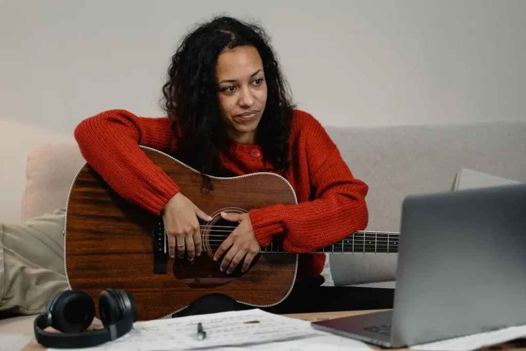 Frustrated adult beginner guitarist sitting with guitar feeling stuck on a playing plateau